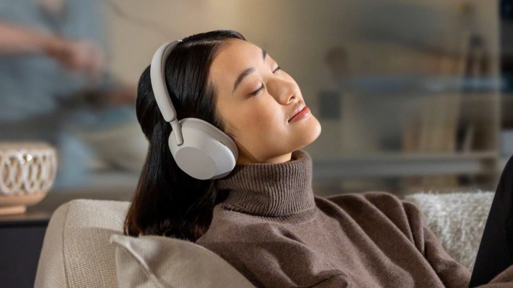 Asian woman with eyes closed wearing Sony WH-1000XM5 noise-cancelling headphones